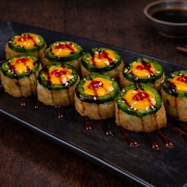 Ten fried sushi rolls topped with jalapeño, orange sauce, sesame seeds, and dark drizzle.